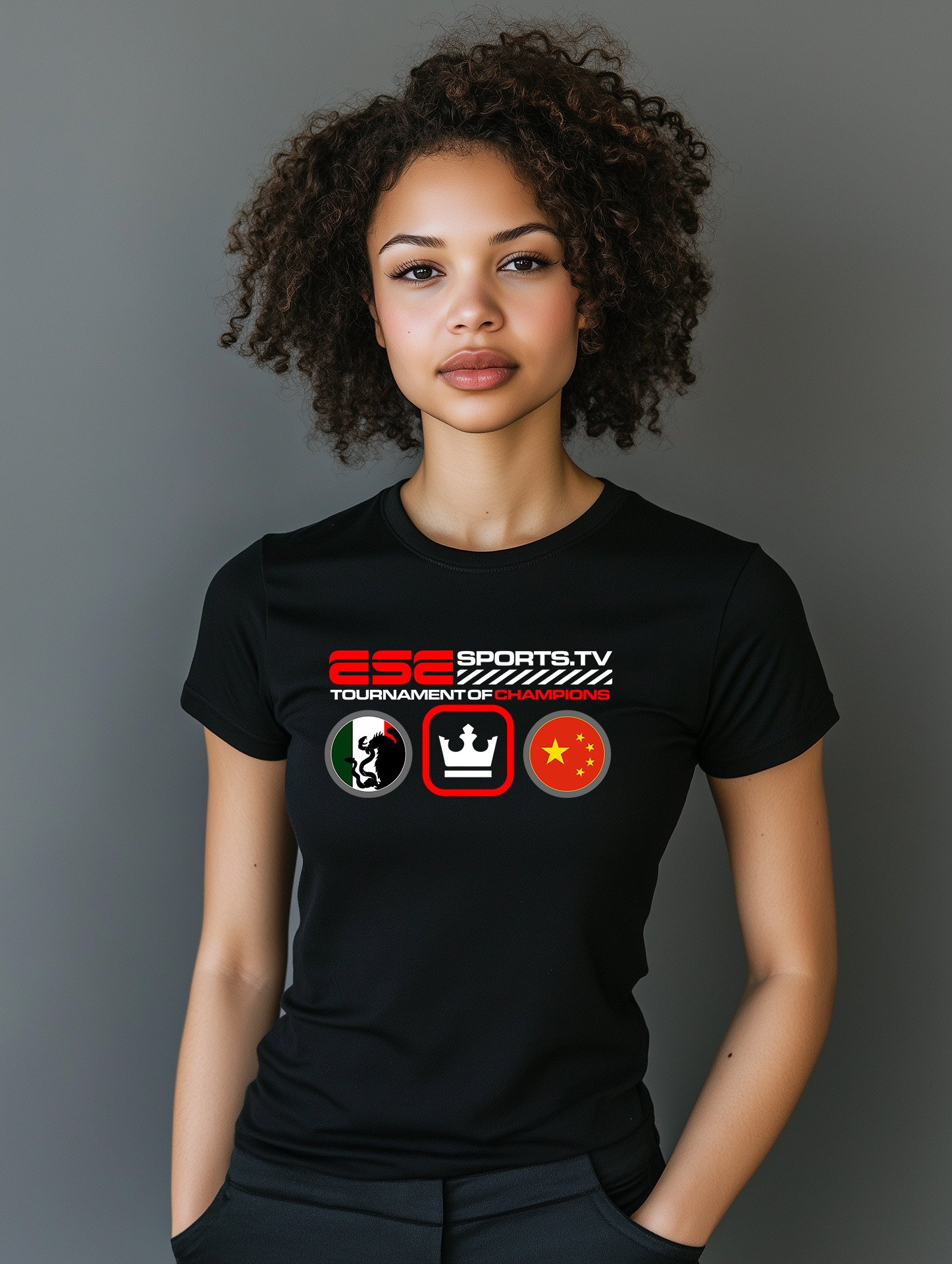 A person with curly hair is wearing a black t-shirt featuring the logo ESC SPORTS.TV and the text TOURNAMENT OF CHAMPIONS. The shirt has flag icons and symbols. They stand against a gray background.